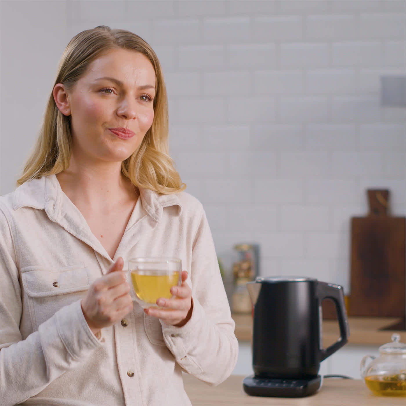 Person hält Tasse mit einem warmen Getränk in der Hand und dahinter steht der Ninja Wasserkocher KT200EU Person hält Tasse mit einem warmen Getränk in der Hand und dahinter steht der Ninja Wasserkocher KT200EU