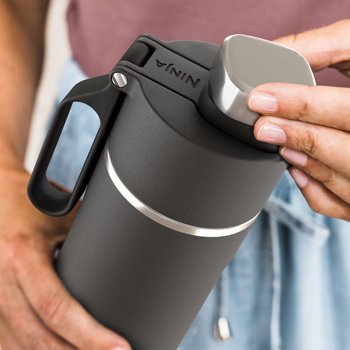 Person öffnet den Deckel des schwarzen Ninja Thermobechers Person öffnet den Deckel des schwarzen Ninja Thermobechers
